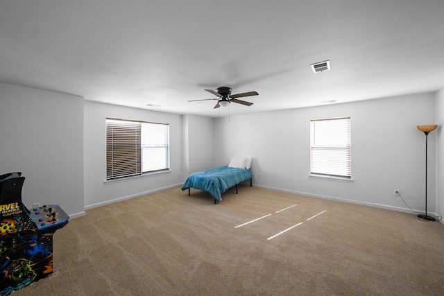 unfurnished bedroom with multiple windows, light colored carpet, and ceiling fan