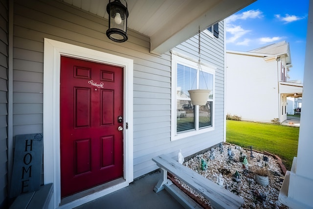 property entrance featuring covered porch and a lawn