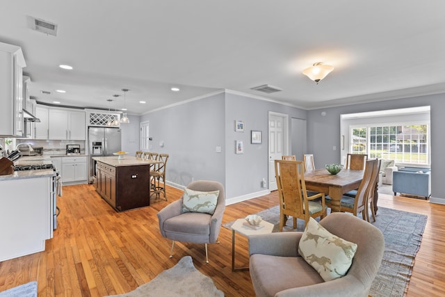 dining room with visible vents, ornamental molding, and light wood-style flooring
