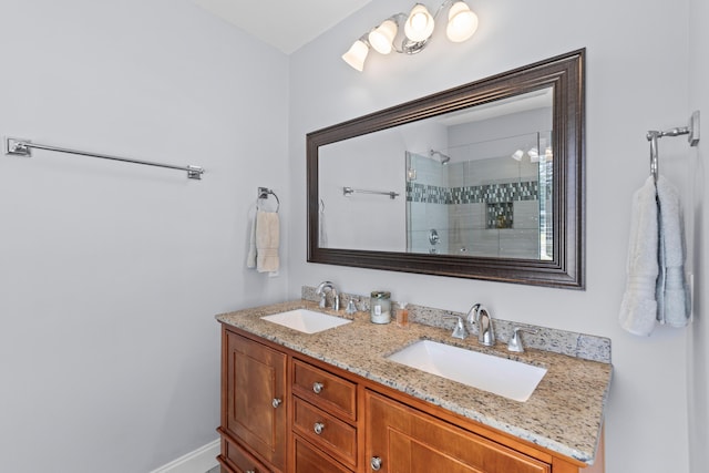 bathroom with tiled shower, double vanity, and a sink