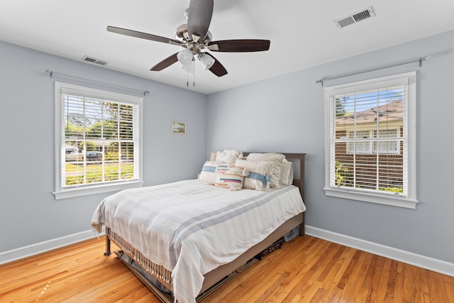 bedroom with light wood finished floors, baseboards, multiple windows, and visible vents