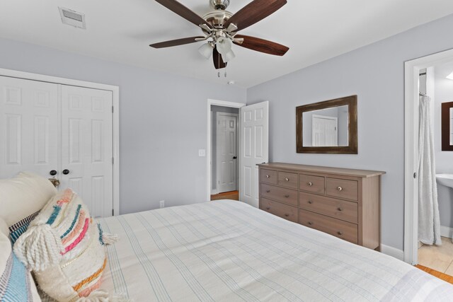 bedroom with ensuite bathroom, a closet, a ceiling fan, visible vents, and baseboards