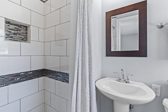 bathroom featuring a sink, a tile shower, and toilet