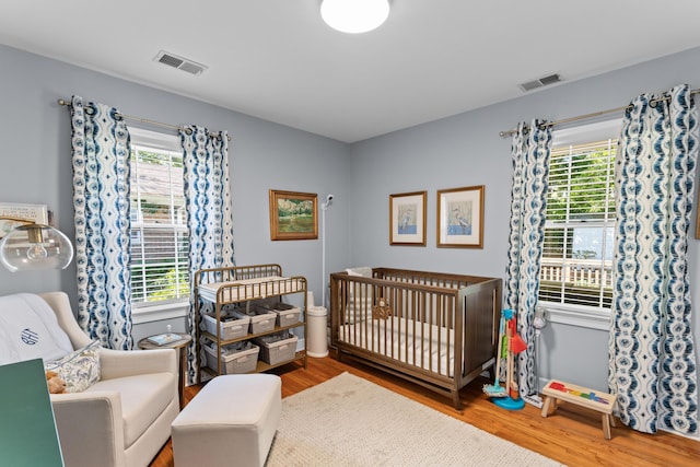 bedroom featuring wood finished floors, multiple windows, and visible vents