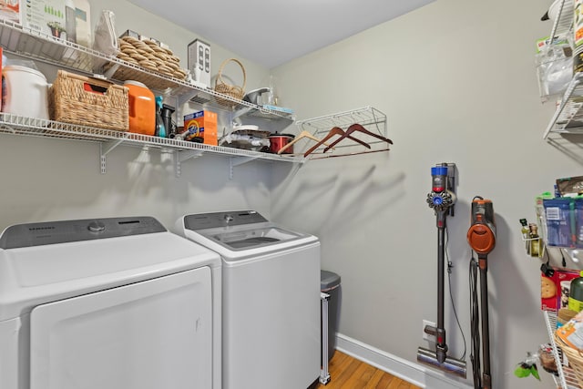 laundry area featuring independent washer and dryer, light wood-type flooring, laundry area, and baseboards