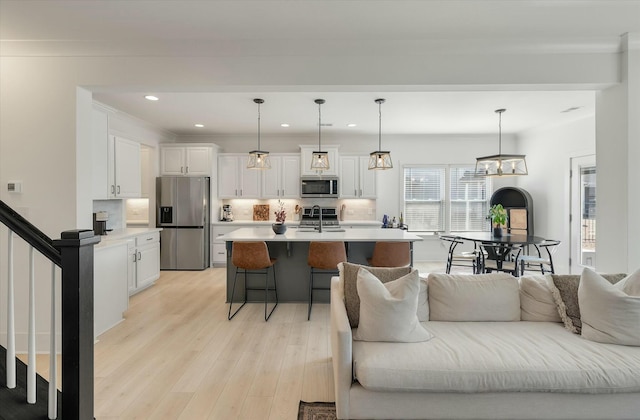 kitchen featuring pendant lighting, white cabinetry, stainless steel appliances, and an island with sink