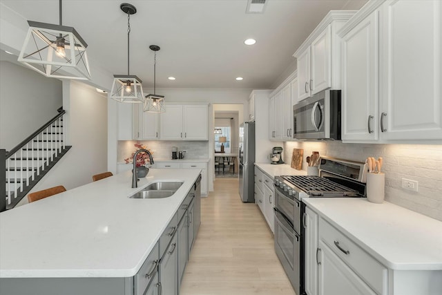 kitchen with pendant lighting, sink, white cabinetry, a kitchen island with sink, and stainless steel appliances