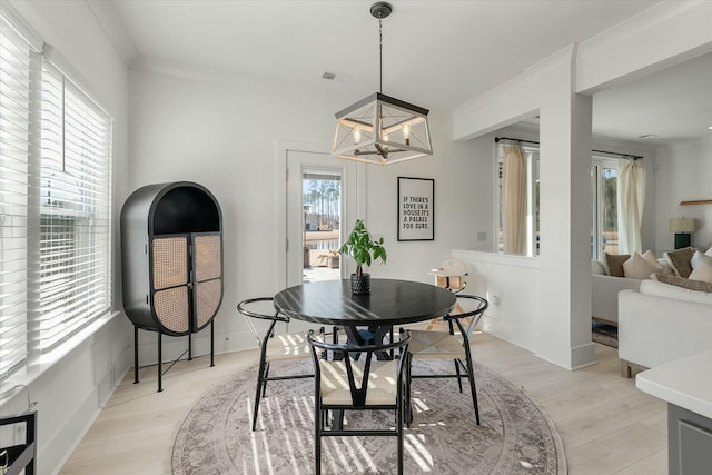 dining space with an inviting chandelier, light hardwood / wood-style flooring, and ornamental molding