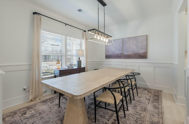 dining area with ornamental molding and light hardwood / wood-style floors