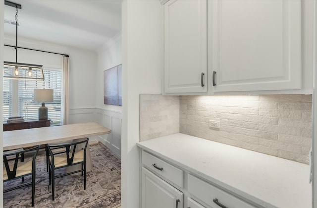 interior space with tasteful backsplash, decorative light fixtures, and white cabinets