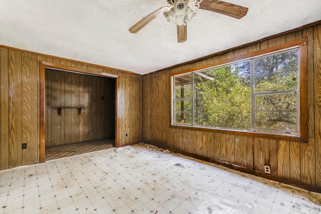 spare room featuring light floors, wooden walls, and a wealth of natural light