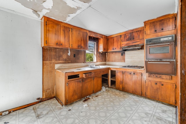 kitchen featuring wall oven, a sink, light countertops, a warming drawer, and light floors