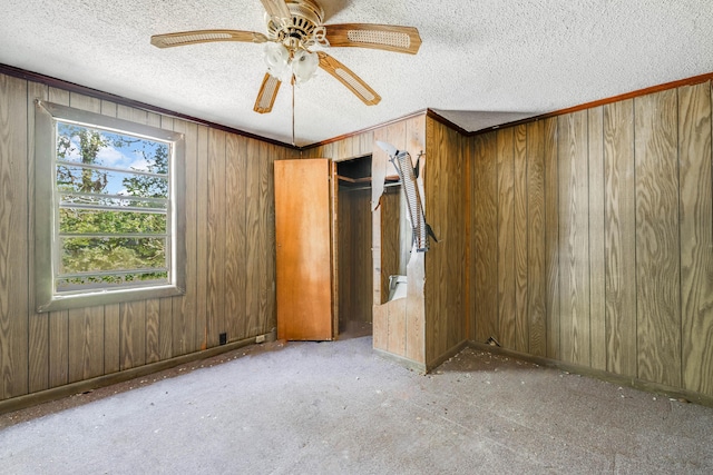 unfurnished bedroom featuring a closet, wooden walls, and a textured ceiling