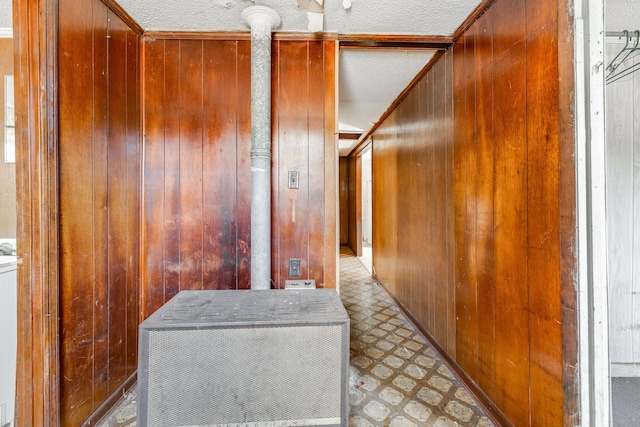 hall featuring a textured ceiling, light floors, and wooden walls