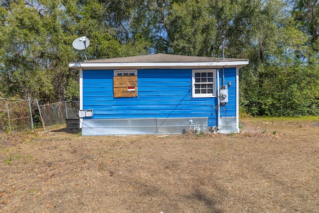 view of home's exterior with an outbuilding and fence