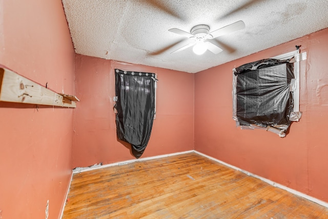 unfurnished room with a textured ceiling, ceiling fan, and wood finished floors