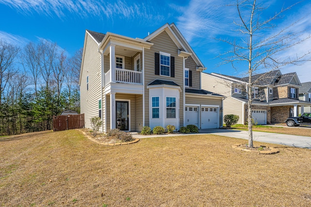 traditional home featuring a front yard, a balcony, driveway, and fence