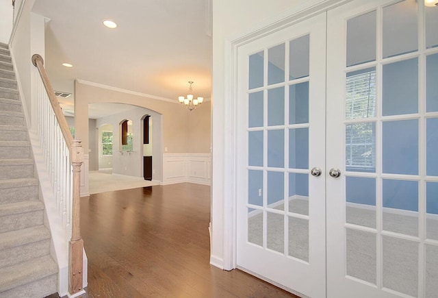 interior space with a wainscoted wall, stairs, french doors, wood finished floors, and a decorative wall