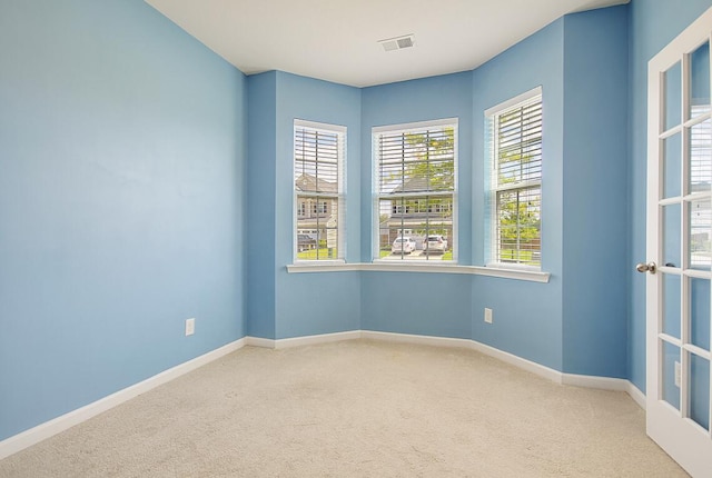 carpeted empty room featuring baseboards and visible vents