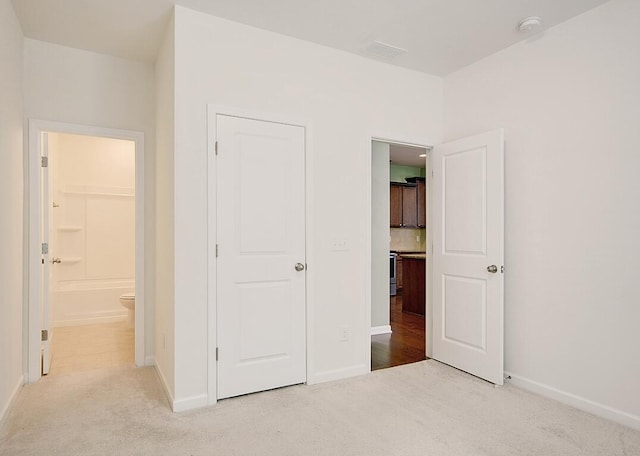 unfurnished bedroom featuring baseboards, carpet floors, and connected bathroom