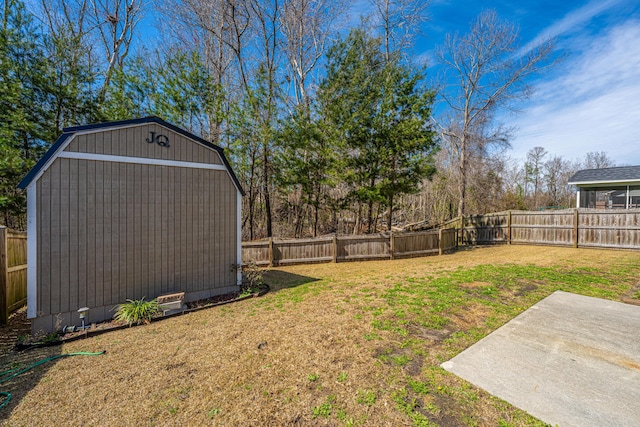 view of yard featuring a garage, a fenced backyard, an outbuilding, a storage unit, and a patio