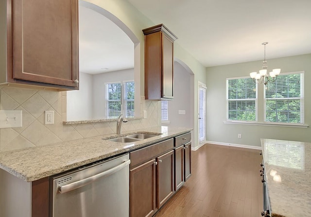 kitchen with light stone counters, wood finished floors, baseboards, a sink, and dishwasher