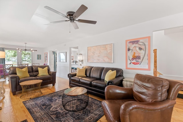 living room with ceiling fan with notable chandelier and light wood-type flooring