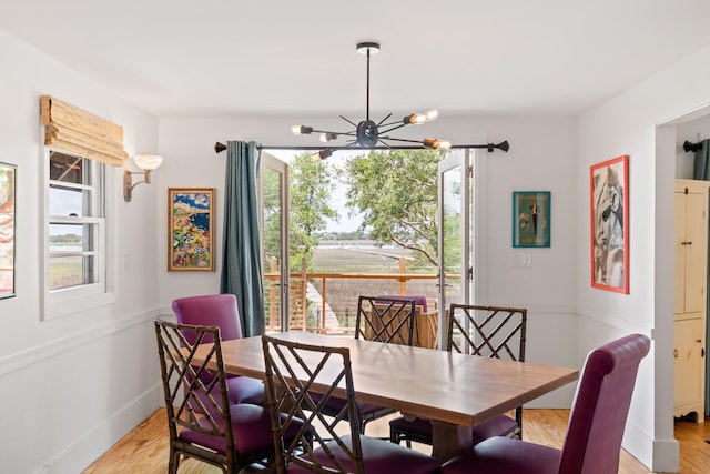 dining room featuring a healthy amount of sunlight, light hardwood / wood-style floors, and a notable chandelier