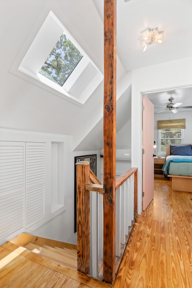 interior space with wood-type flooring, lofted ceiling with skylight, and ceiling fan