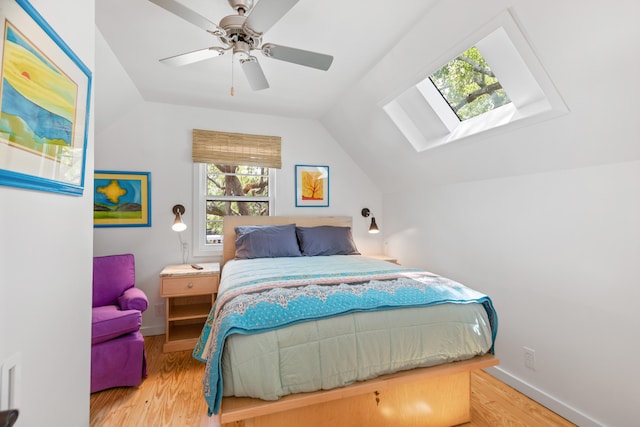 bedroom featuring vaulted ceiling with skylight, ceiling fan, and hardwood / wood-style flooring