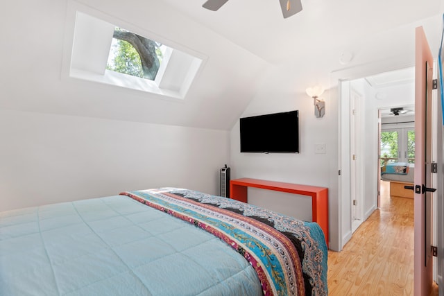 bedroom featuring wood-type flooring, vaulted ceiling with skylight, and ceiling fan