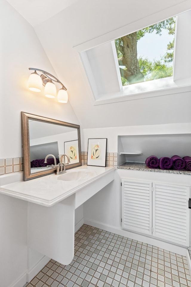 bathroom featuring vaulted ceiling, sink, and tile patterned floors