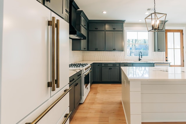 kitchen with pendant lighting, decorative backsplash, light wood-style flooring, white appliances, and a sink