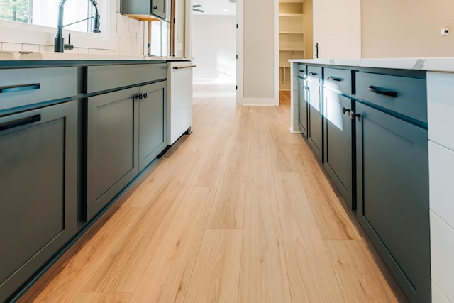 kitchen featuring light wood finished floors, dishwasher, tasteful backsplash, and light countertops