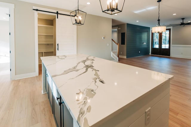 kitchen with light wood-type flooring, open floor plan, recessed lighting, a barn door, and french doors