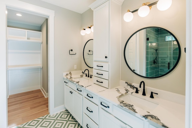 full bathroom with a spacious closet, baseboards, a stall shower, and a sink