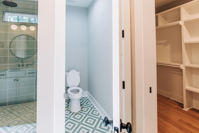 full bathroom with baseboards, toilet, wood finished floors, and a shower stall