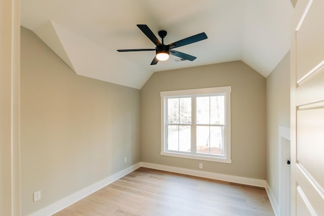 spare room featuring light wood finished floors, baseboards, a ceiling fan, and vaulted ceiling