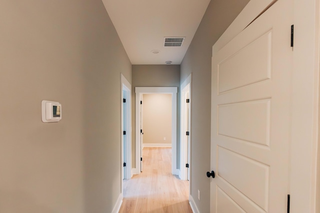 corridor featuring light wood-style flooring, baseboards, and visible vents