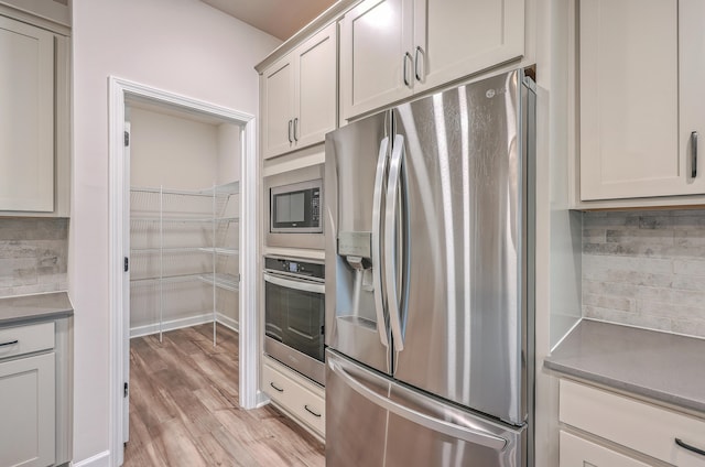 kitchen featuring backsplash, light hardwood / wood-style flooring, and stainless steel appliances