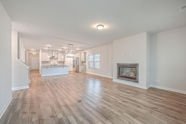 unfurnished living room with sink and light wood-type flooring