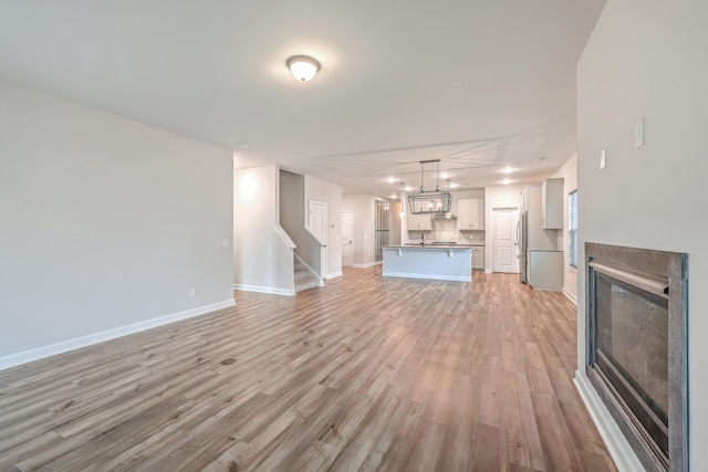 unfurnished living room with light hardwood / wood-style floors and an inviting chandelier