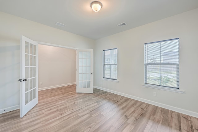 empty room with light hardwood / wood-style flooring and french doors