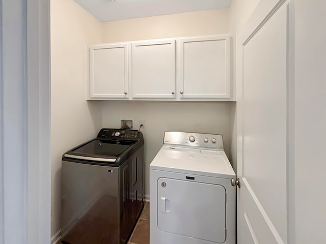 laundry area featuring dark tile patterned flooring, cabinets, and washing machine and clothes dryer