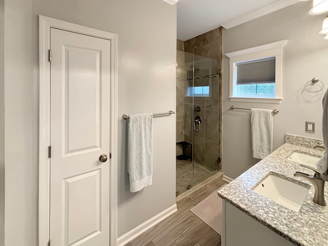 bathroom featuring ornamental molding, a shower with door, wood-type flooring, and vanity