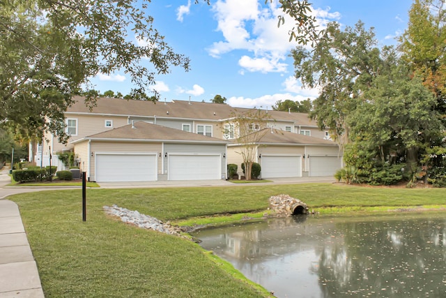 view of front of property with a garage, a water view, and a front lawn