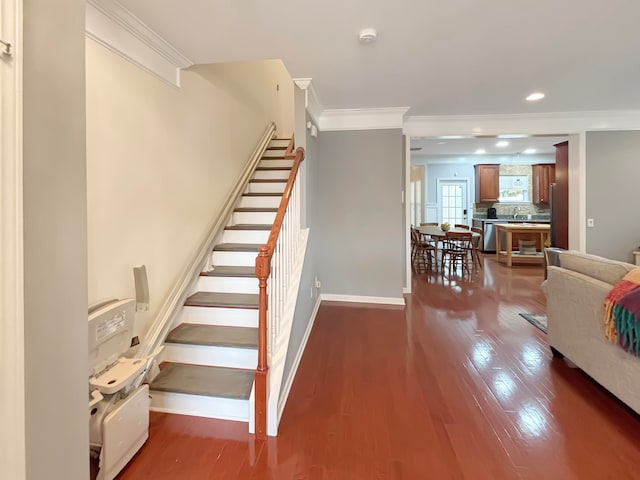 stairway with wood-type flooring and crown molding