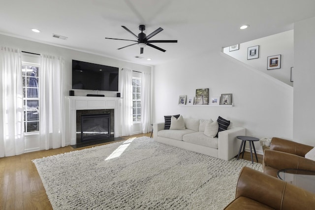 living room featuring recessed lighting, a fireplace with flush hearth, wood finished floors, visible vents, and a ceiling fan