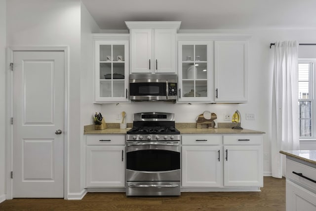 kitchen featuring dark wood-type flooring, white cabinetry, appliances with stainless steel finishes, light stone countertops, and glass insert cabinets