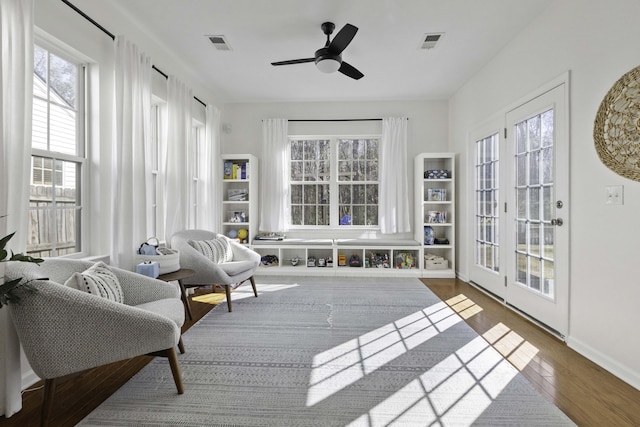 living area featuring visible vents, ceiling fan, baseboards, and wood finished floors